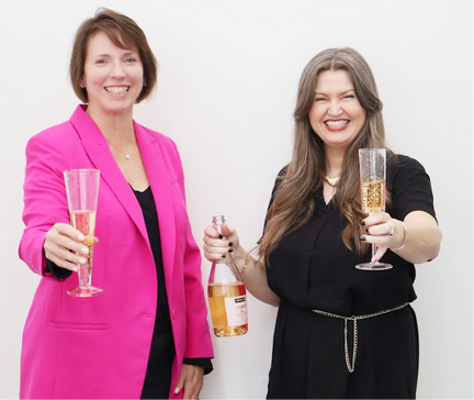Two women with champagne saluting toward the viewer