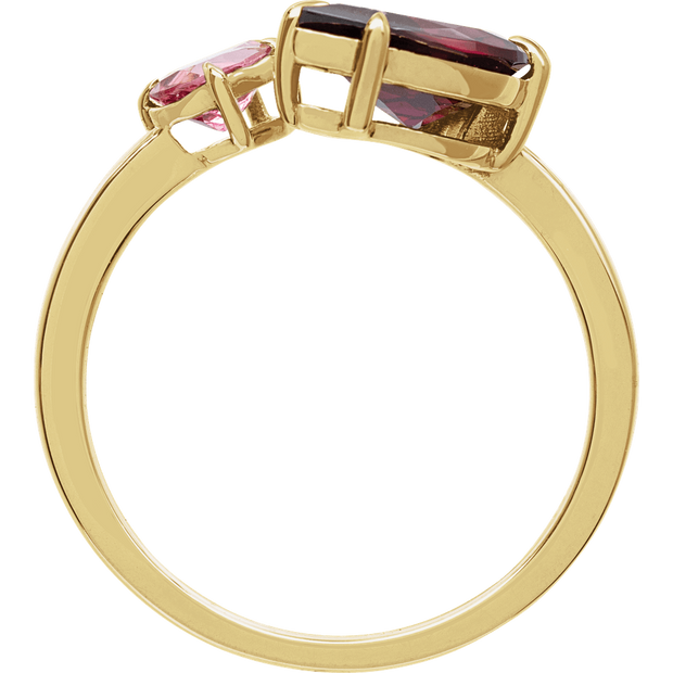 Gold ring with red and pink gemstones on a white background