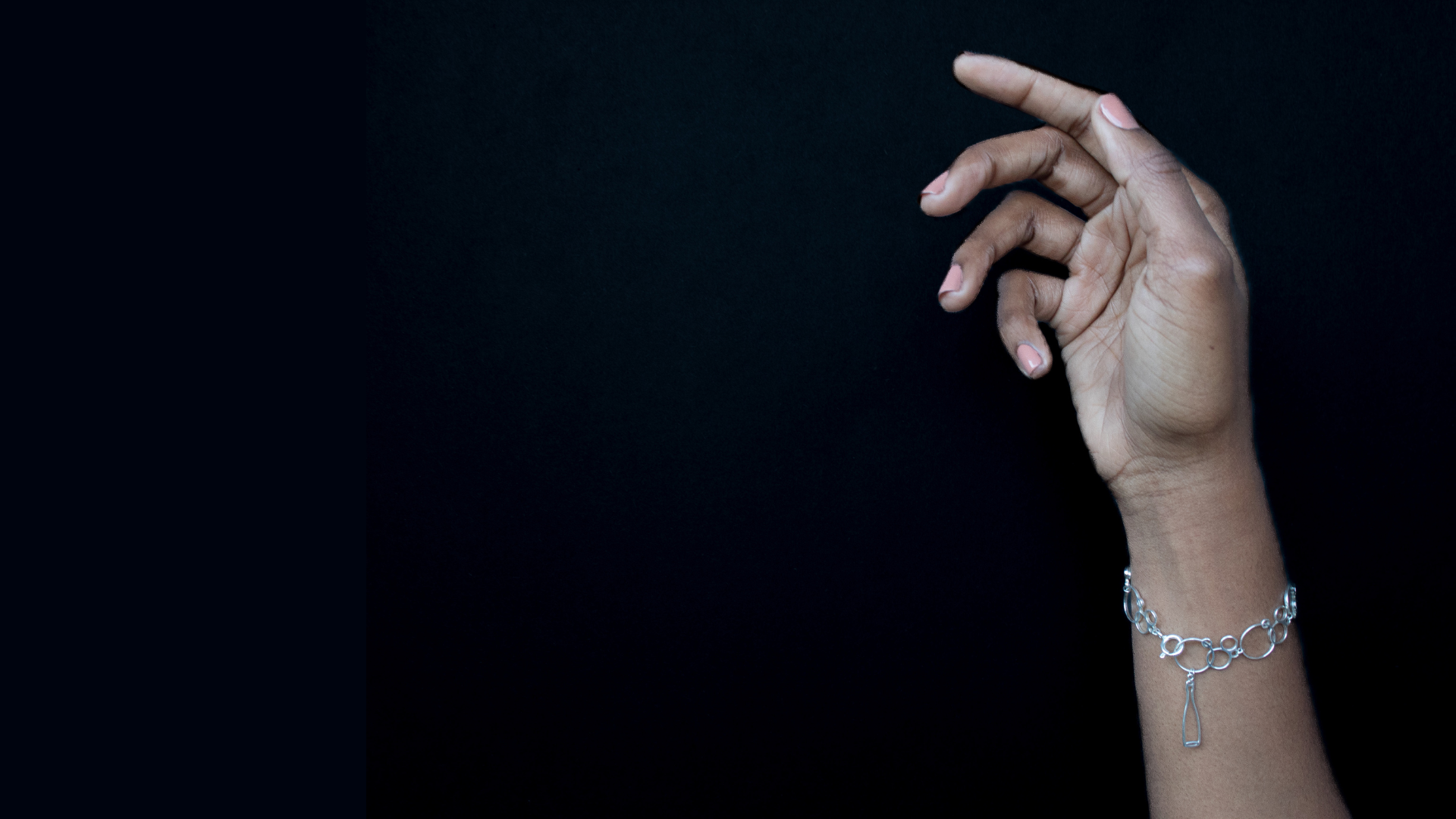 Hand with a silver bracelet on a black background